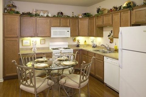 A kitchen with a table set for two and a white refrigerator.