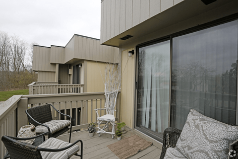 A balcony with a couch, chairs and a table.