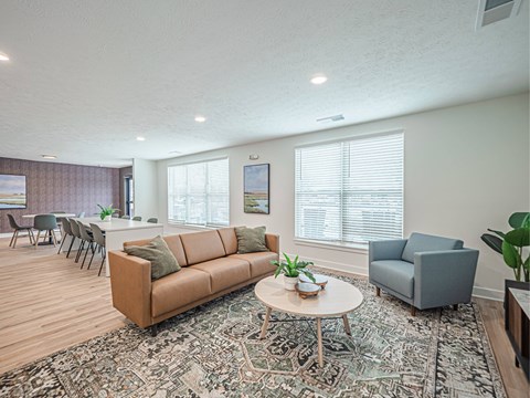 A living room with a brown couch and a round table with a plant on it.