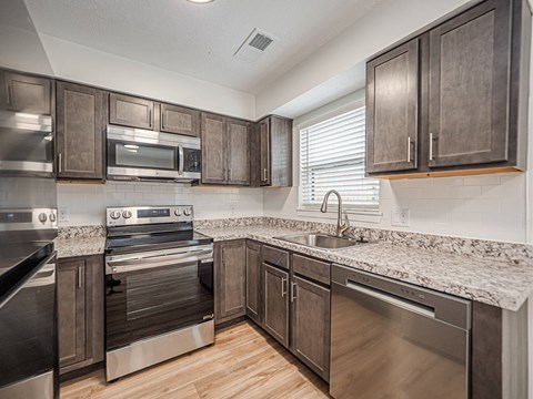 A kitchen with dark wood cabinets and stainless steel appliances.