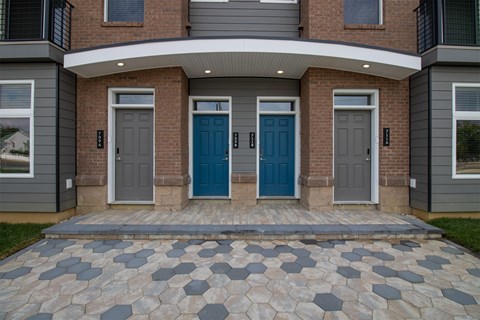 A house with a grey front yard and a blue door.