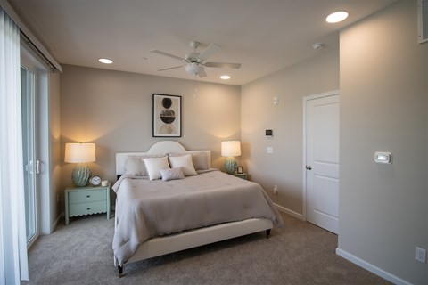 A bedroom with a large bed and a ceiling fan.