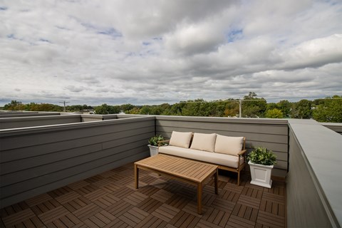 A wooden table and couch are on a wooden deck.