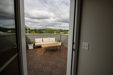 A balcony with a bench and potted plants.