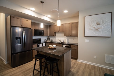 A kitchen with a refrigerator, stove, and bar stools.