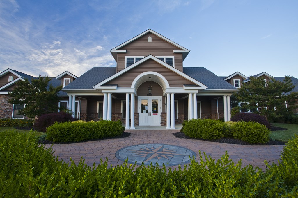 the front of a house with a porch and a clock on the ground