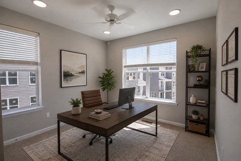 A room with a desk, chair, and a fan.