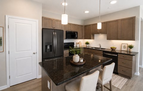 A kitchen with a black granite countertop and white chairs.