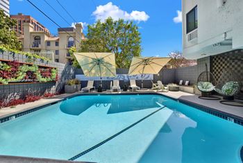 A swimming pool with a yellow umbrella and a white chair.