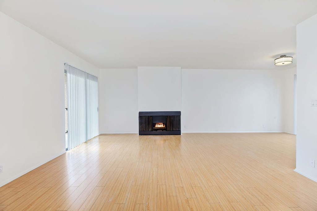 Open living room angle from dining room and sliding glass balcony door featuring the fireplace