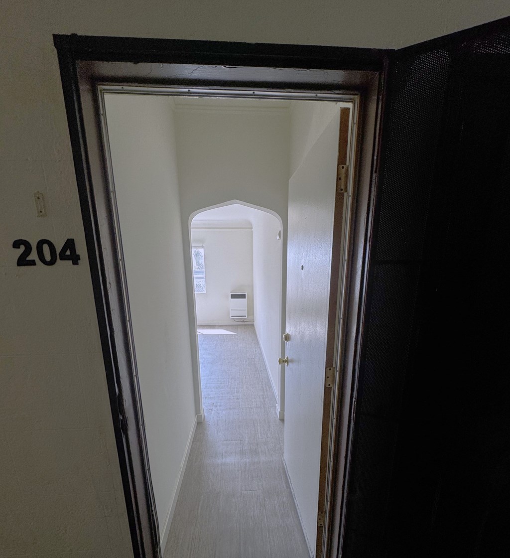 A hallway with a door at the end and a number 204 on the wall.