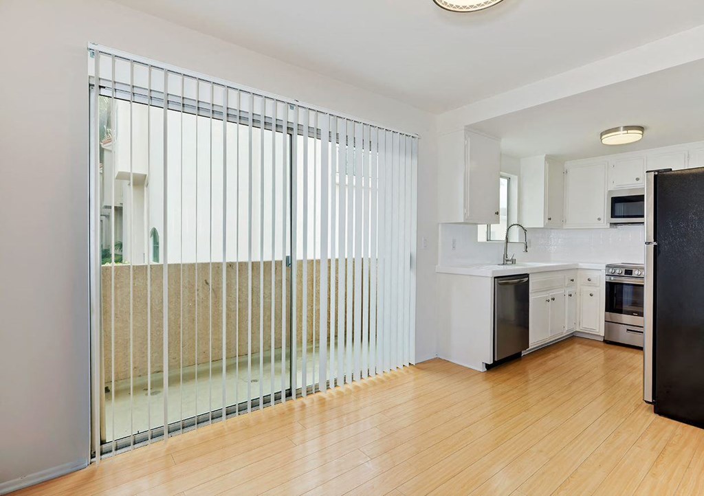 Balcony sliding glass door next to open kitchen adjacent to dining room