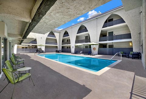A large swimming pool is surrounded by chairs and tables.
