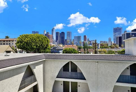 A concrete building with arched windows overlooks a city skyline.