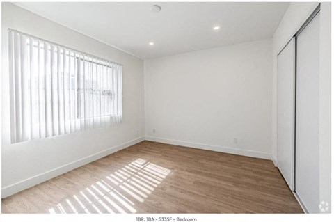 an empty living room with a large window and wooden floors