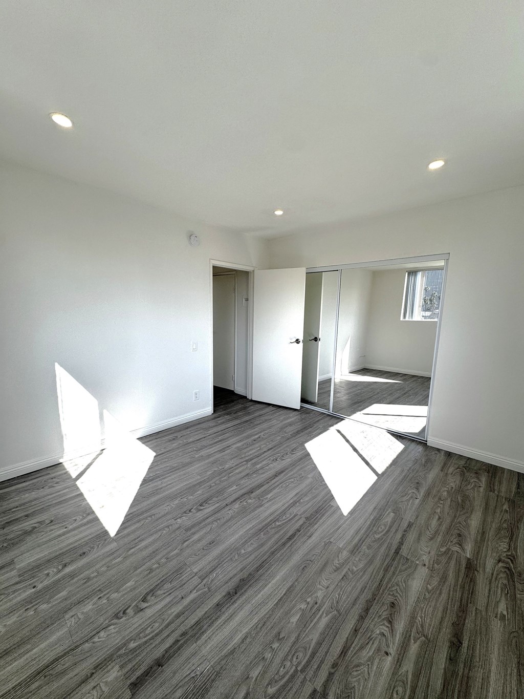 A room with wooden flooring and white walls.