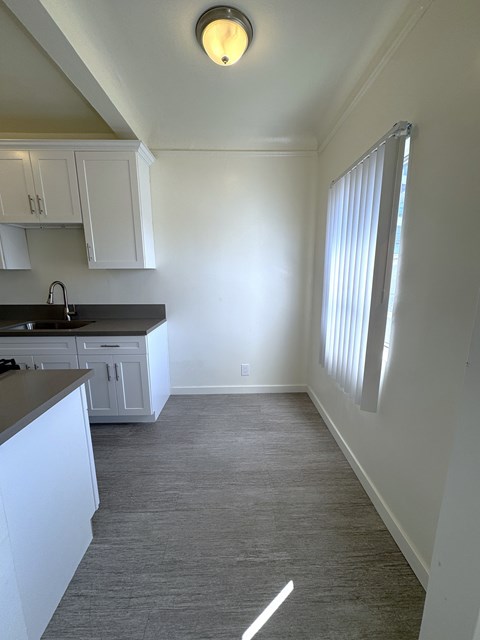 A kitchen with white cabinets and a black countertop.