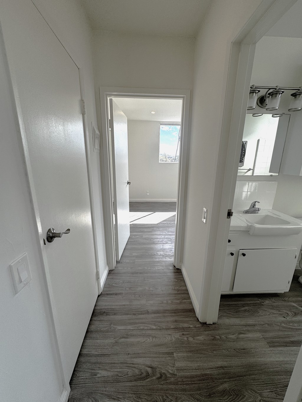 A long white hallway with a bathroom at the end.