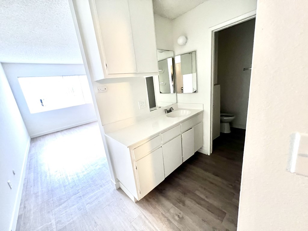 Bachelor style unit vanity white counter tops and cabinets with sink and faucet outside bathroom