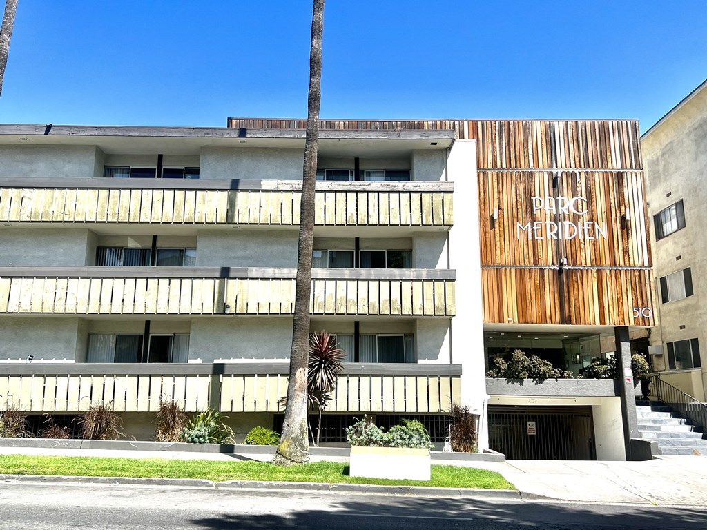 Exterior building view from Normandie St. featuring balconies three floors, garage and lobby entrance  at Parc Meridien, California