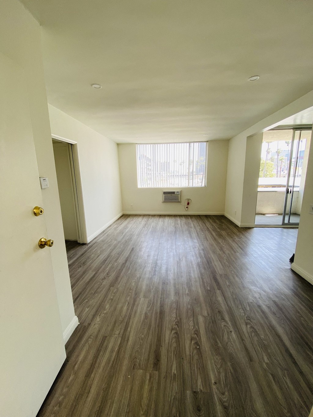 an empty living room with wooden floors and a window