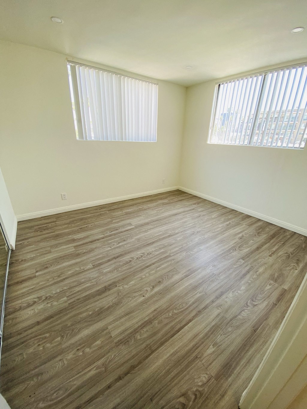 an empty room with wood flooring and two windows