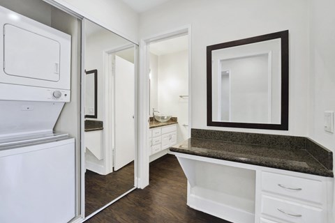 A white kitchen with a granite counter top and a refrigerator.