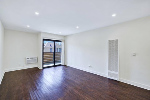 A room with wooden floors and a window with a view of a building outside.