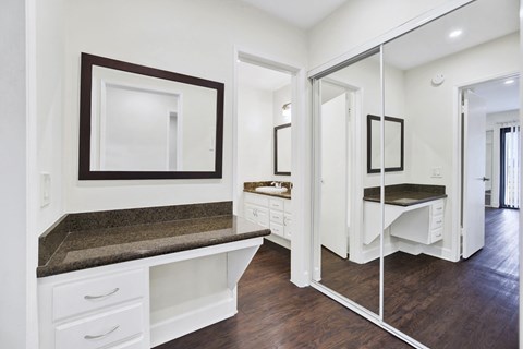 A white kitchen with a marble countertop and a mirror above it.