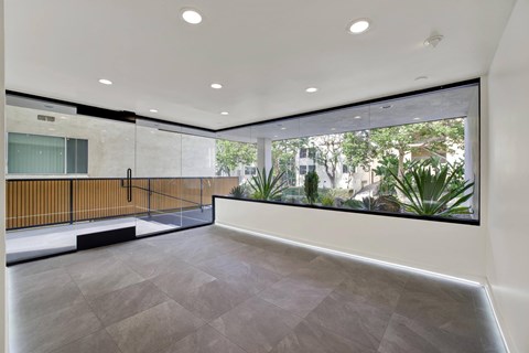 A spacious room with a grey floor and a large window overlooking a garden.
