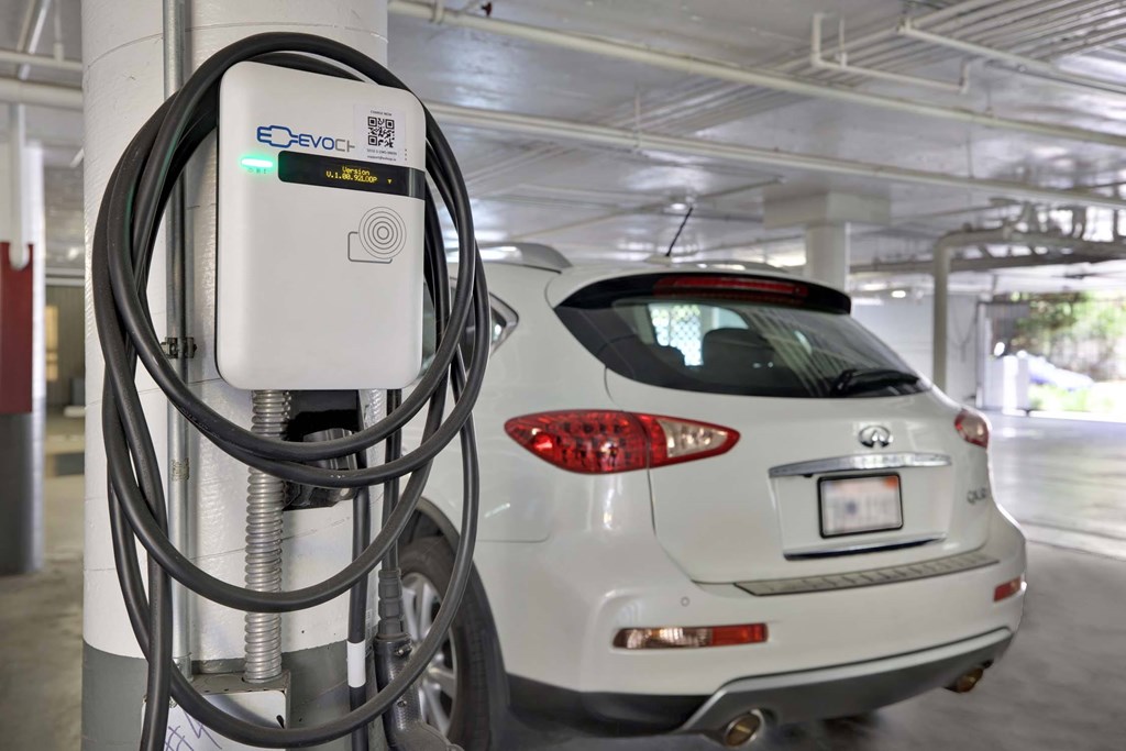 A white car is plugged into an E-Devoch charging station.