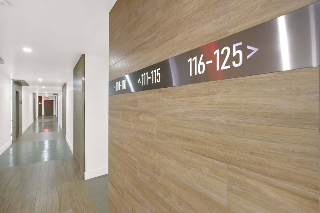 A long hallway with a wall that has a sign that says 111-115 and 116-125.