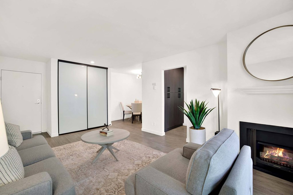 A living room with a grey couch, a coffee table, a fireplace, and a plant.