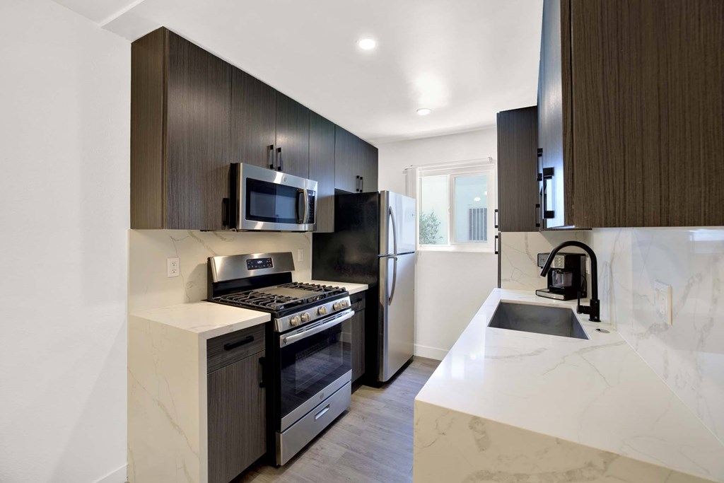 A modern kitchen with dark brown cabinets and white countertops.