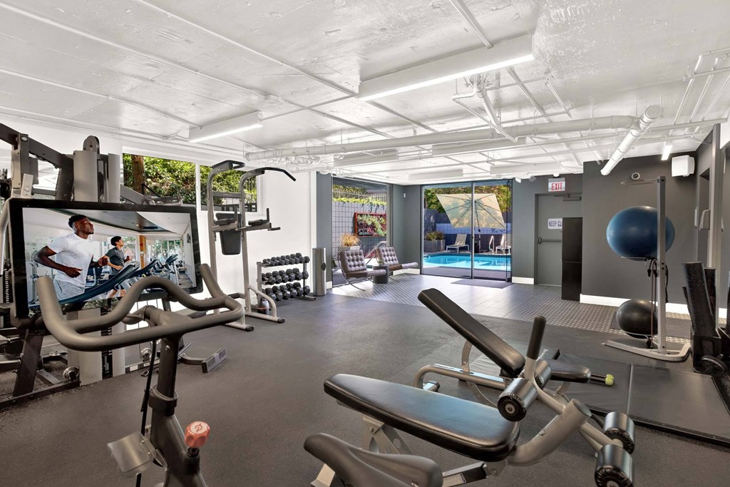 A gym with a variety of equipment including treadmills, weights, and exercise balls.