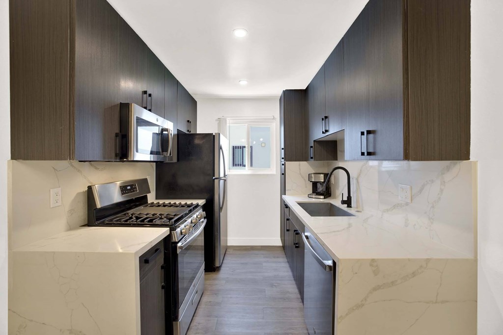 A modern kitchen with dark brown cabinets and a marble countertop.