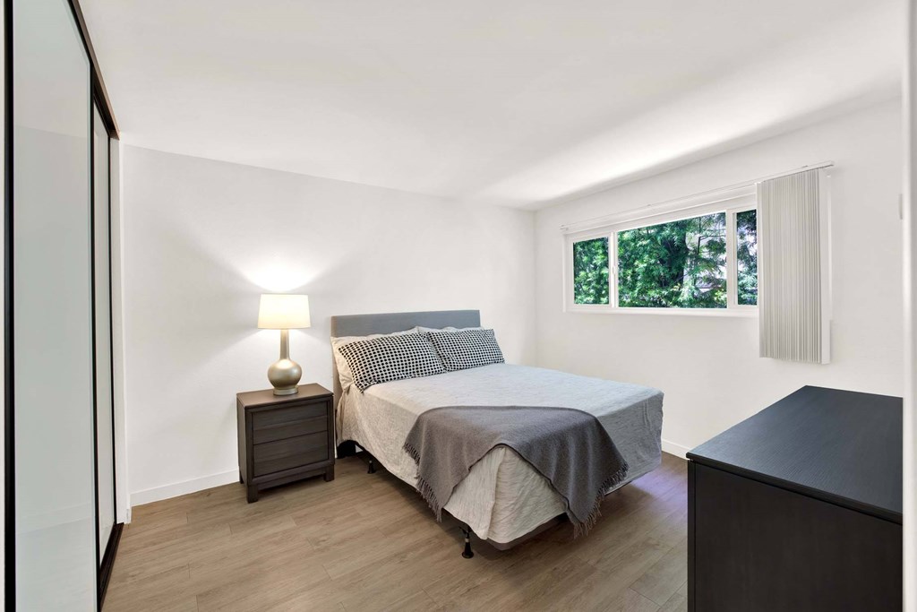 A bedroom with a bed, nightstand, and lamp.