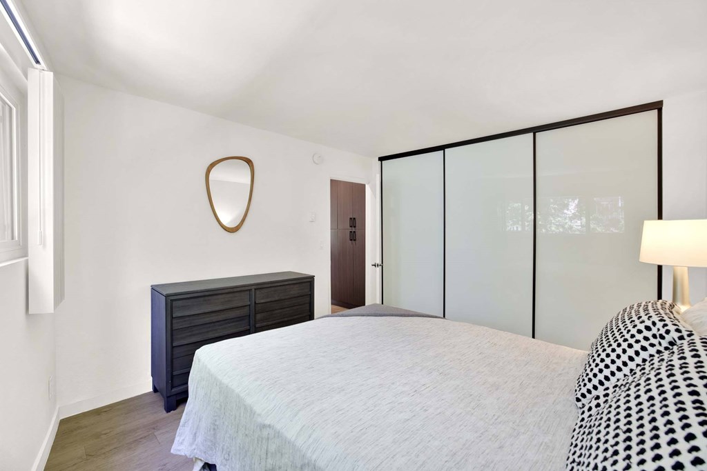 A bedroom with a bed, dresser, and mirror.