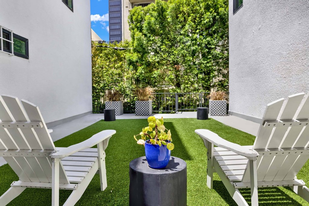 Two white chairs are placed on a green lawn.