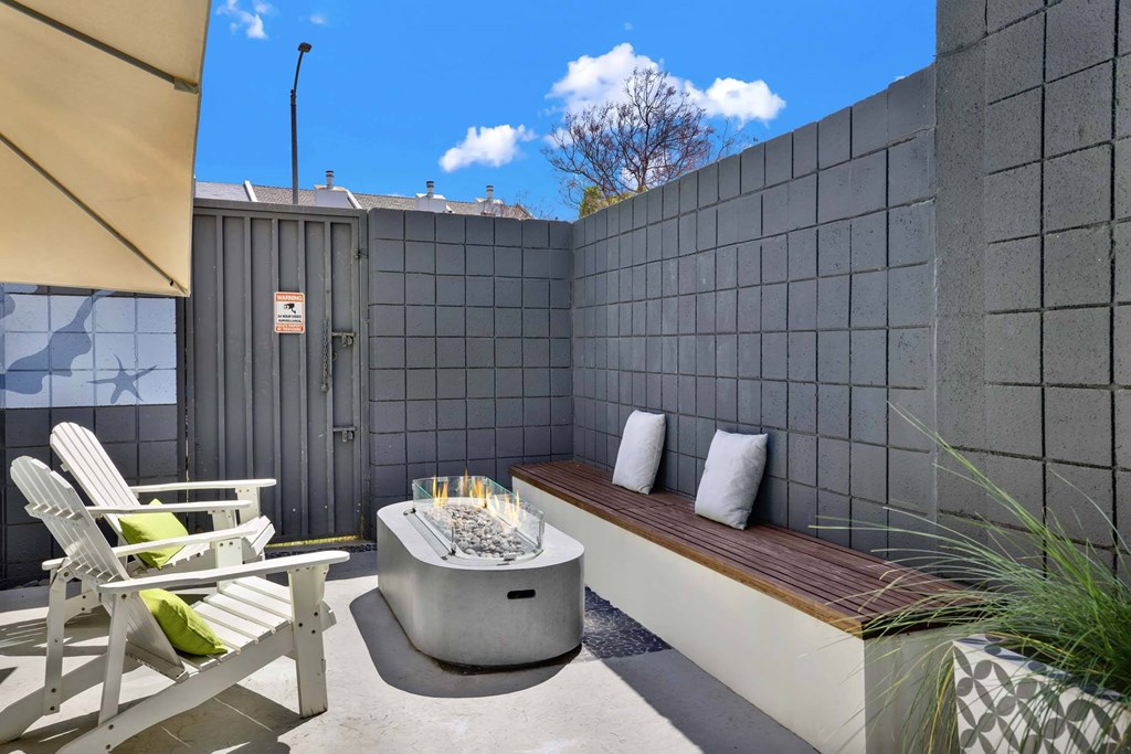 A patio with a hot tub, chairs, and a bench.