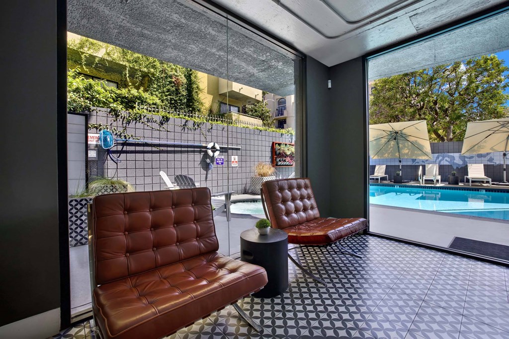 Two brown leather chairs are placed in a room with a glass wall.