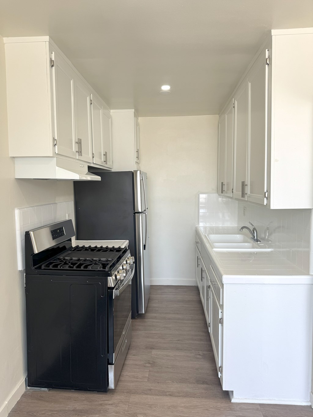A black stove and refrigerator in a kitchen with white cabinets.