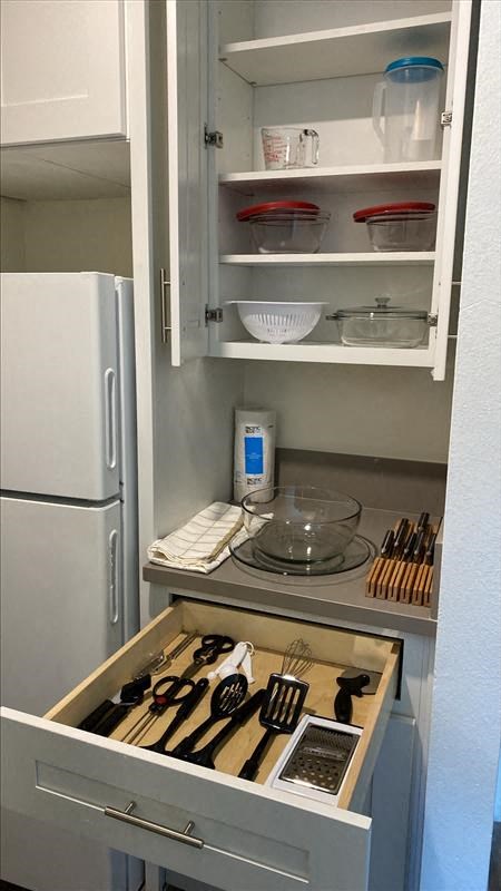 a kitchen with a refrigerator and a cabinet with kitchen utensils