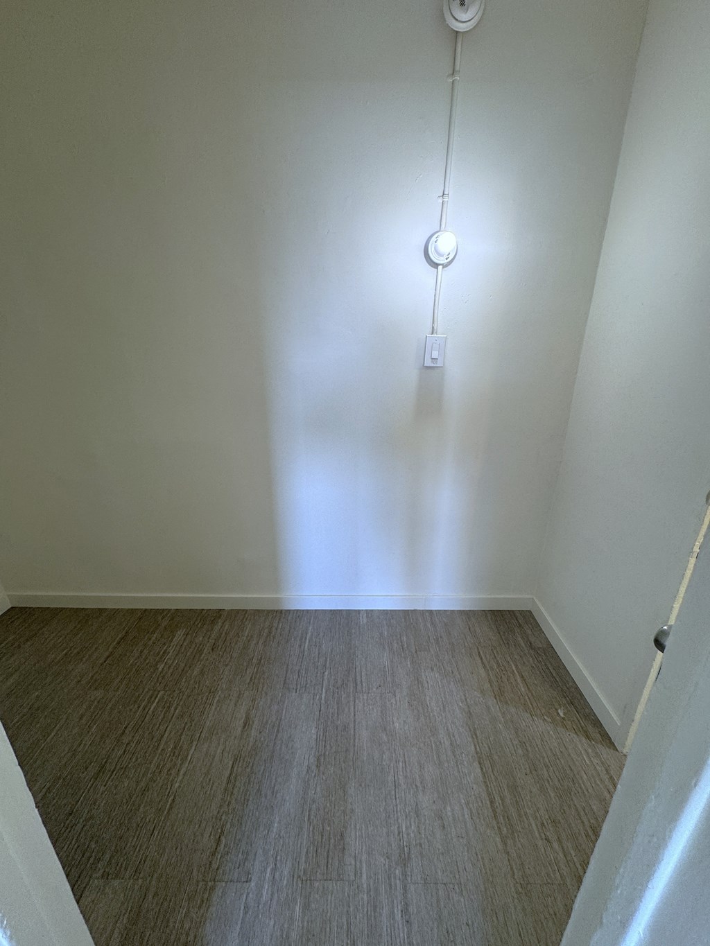 A white wall with a light bulb hanging from it.