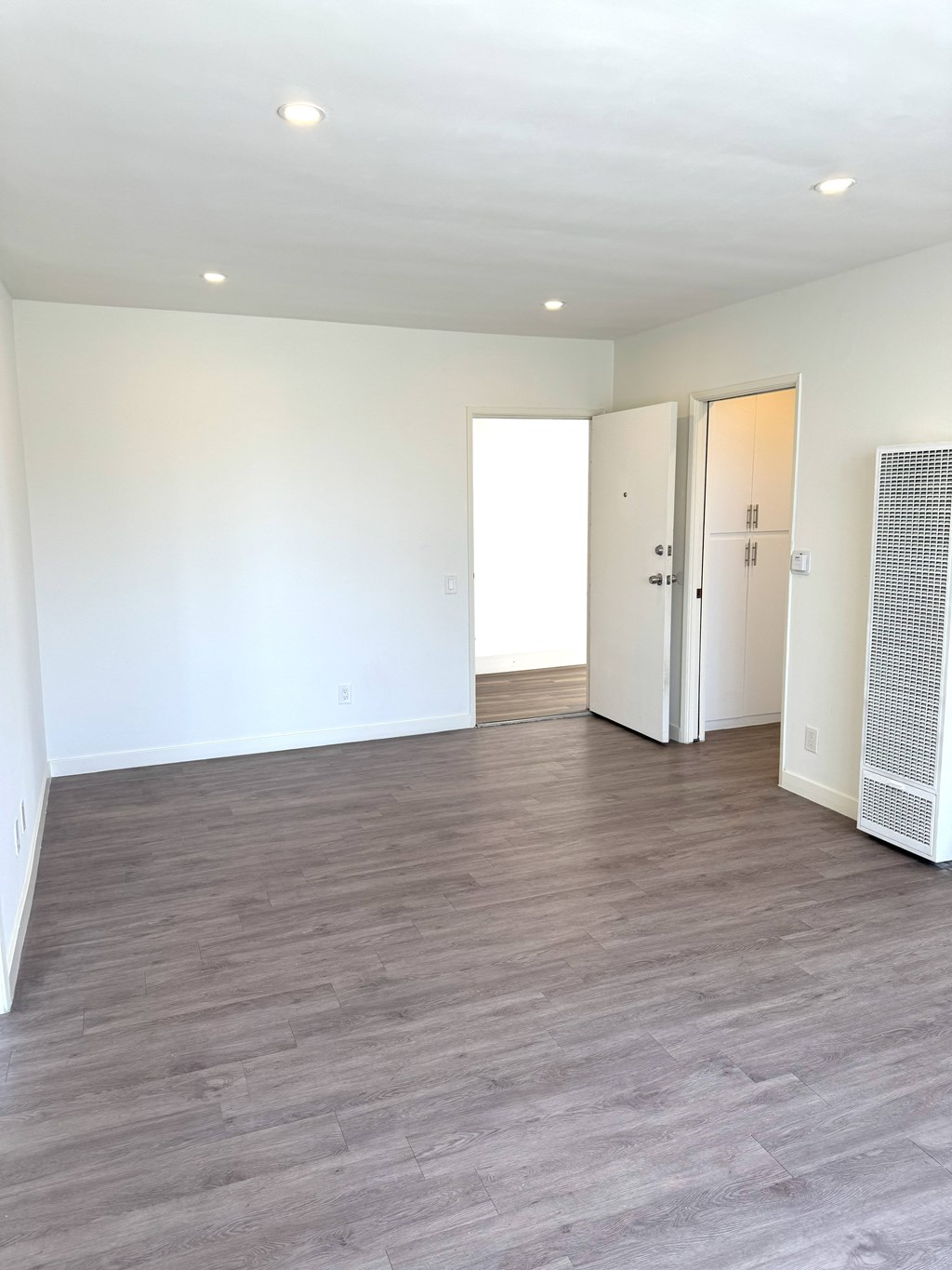 A room with a wooden floor and a white wall.