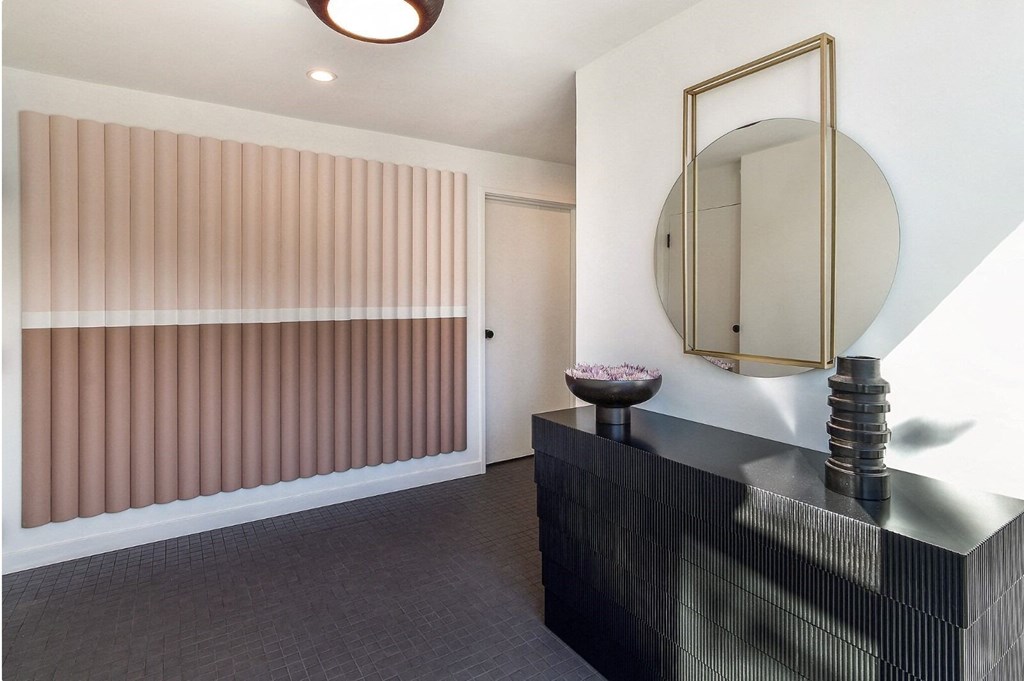 a hallway with a black dresser and a mirror and a door