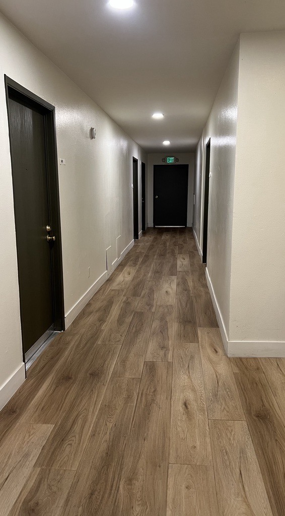 a hallway with wooden floors and white walls and black doors