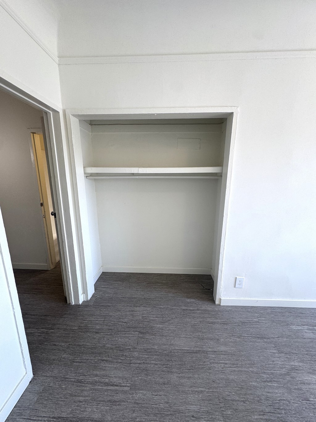 A white closet with a shelf and a door open.