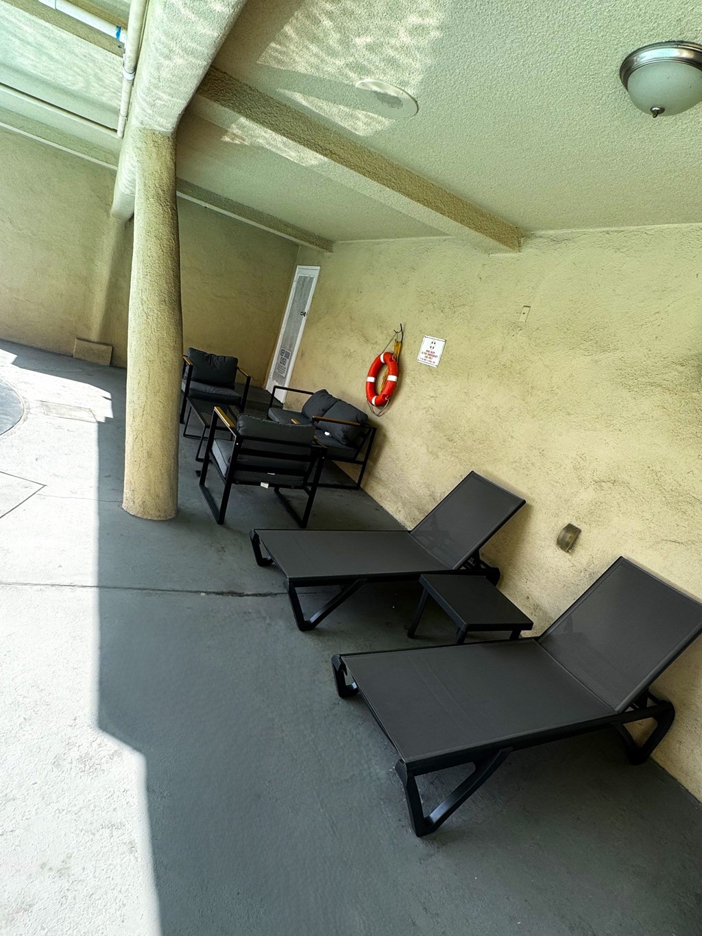 A patio with black chairs and a red life preserver on the wall.