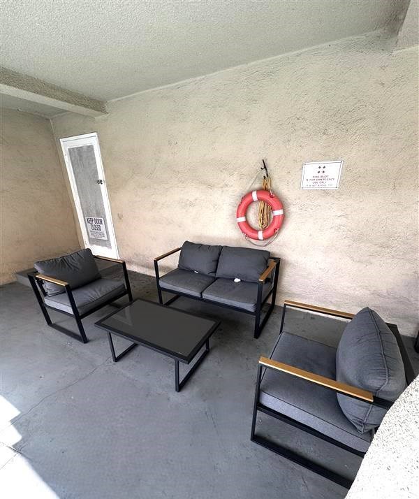 A living room with black furniture and a life preserver on the wall.